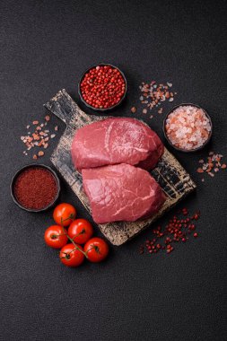 Koyu beton zeminde tuzlu ve baharatlı çiğ sığır filetosu bifteği.