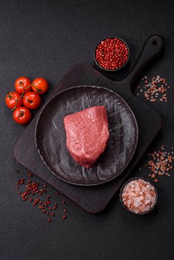 Koyu beton zeminde tuzlu ve baharatlı çiğ sığır filetosu bifteği.