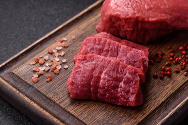 Koyu beton zeminde tuzlu ve baharatlı çiğ sığır filetosu bifteği.