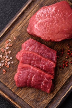 Koyu beton zeminde tuzlu ve baharatlı çiğ sığır filetosu bifteği.
