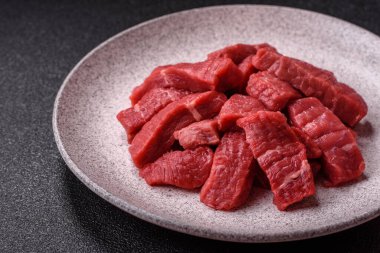 Çiğ sığır filetosu, koyu beton arka planda tuz ve baharatla dilimlenmiş.