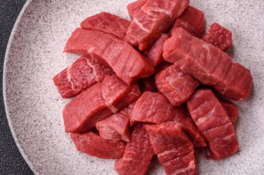 Çiğ sığır filetosu, koyu beton arka planda tuz ve baharatla dilimlenmiş.