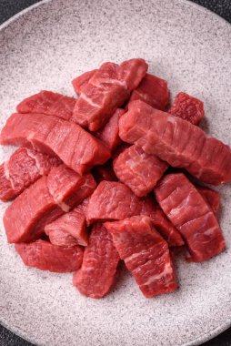 Çiğ sığır filetosu, koyu beton arka planda tuz ve baharatla dilimlenmiş.