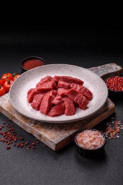 Çiğ sığır filetosu, koyu beton arka planda tuz ve baharatla dilimlenmiş.