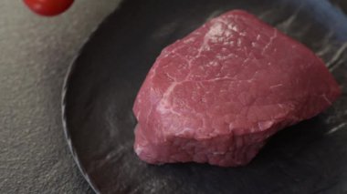 Koyu beton zeminde tuzlu ve baharatlı çiğ sığır filetosu bifteği.