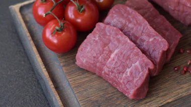 Koyu beton zeminde tuzlu ve baharatlı çiğ sığır filetosu bifteği.