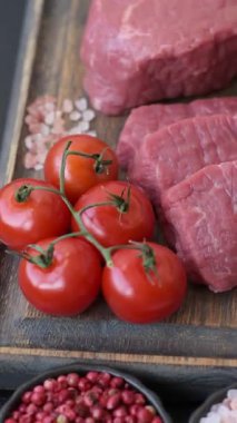 Çiğ sığır filetosu, koyu beton arka planda tuz ve baharatla dilimlenmiş.