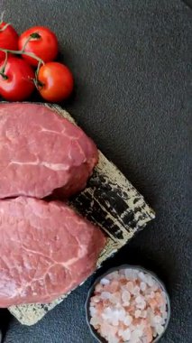 Koyu beton zeminde tuzlu ve baharatlı çiğ sığır filetosu bifteği.