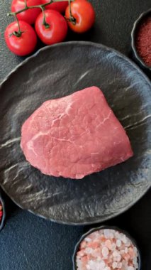 Koyu beton zeminde tuzlu ve baharatlı çiğ sığır filetosu bifteği.