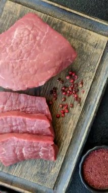 Koyu beton zeminde tuzlu ve baharatlı çiğ sığır filetosu bifteği.