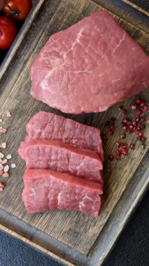 Koyu beton zeminde tuzlu ve baharatlı çiğ sığır filetosu bifteği.