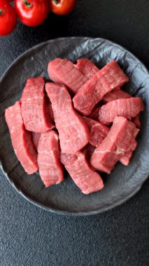 Çiğ sığır filetosu, koyu beton arka planda tuz ve baharatla dilimlenmiş.