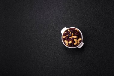 Koyu beton arka planda kavrulmuş kaju ve kurutulmuş kızılcık karışımı.