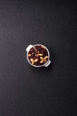 Koyu beton arka planda kavrulmuş kaju ve kurutulmuş kızılcık karışımı.