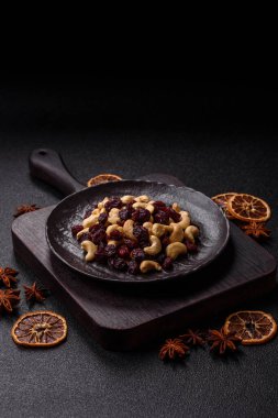 Koyu beton arka planda kavrulmuş kaju ve kurutulmuş kızılcık karışımı.