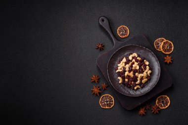 Koyu beton arka planda kavrulmuş kaju ve kurutulmuş kızılcık karışımı.