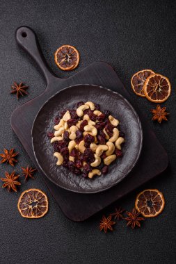 Koyu beton arka planda kavrulmuş kaju ve kurutulmuş kızılcık karışımı.