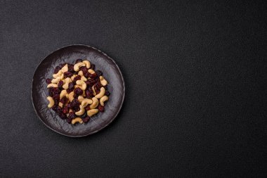 Koyu beton arka planda kavrulmuş kaju ve kurutulmuş kızılcık karışımı.