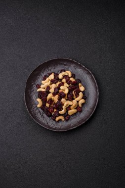 Koyu beton arka planda kavrulmuş kaju ve kurutulmuş kızılcık karışımı.