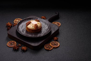 Beyaz narenciye kremalı ve fındıklı, koyu beton kaplamalı tatlı turta.