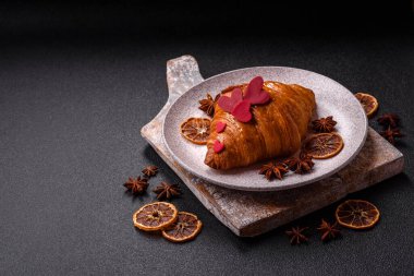 Kırmızı kalpler ve ahududu aromalı kremayla süslenmiş çıtır kruvasan.