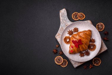 Kırmızı kalpler ve ahududu aromalı kremayla süslenmiş çıtır kruvasan.