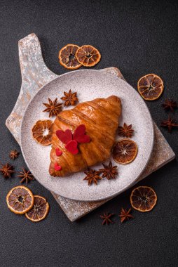 Kırmızı kalpler ve ahududu aromalı kremayla süslenmiş çıtır kruvasan.