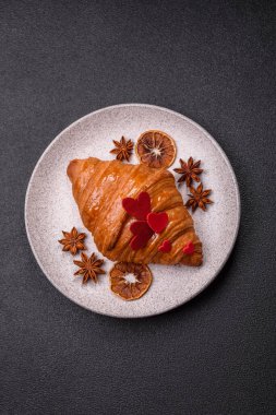 Kırmızı kalpler ve ahududu aromalı kremayla süslenmiş çıtır kruvasan.