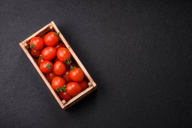 Koyu beton arka planda, tahta bir kutuda olgun kırmızı domatesler.