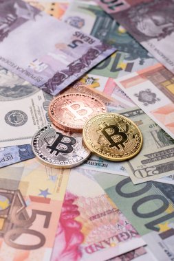Farklı para birimlerinin kağıt banknotlarının arka planında yuvarlak metal bitcoin. Tasarımınız için arkaplan