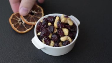 Koyu beton arka planda kavrulmuş kaju ve kurutulmuş kızılcık karışımı.