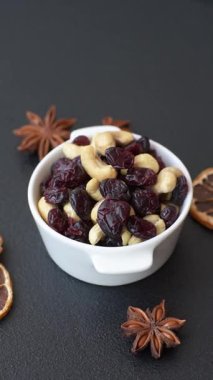 Koyu beton arka planda kavrulmuş kaju ve kurutulmuş kızılcık karışımı.