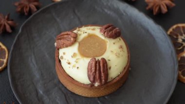 Beyaz narenciye kremalı ve fındıklı, koyu beton kaplamalı tatlı turta.