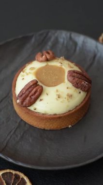 Beyaz narenciye kremalı ve fındıklı, koyu beton kaplamalı tatlı turta.