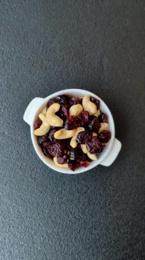 Koyu beton arka planda kavrulmuş kaju ve kurutulmuş kızılcık karışımı.