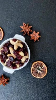 Koyu beton arka planda kavrulmuş kaju ve kurutulmuş kızılcık karışımı.