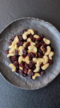 Koyu beton arka planda kavrulmuş kaju ve kurutulmuş kızılcık karışımı.