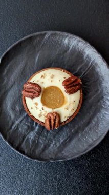 Beyaz narenciye kremalı ve fındıklı, koyu beton kaplamalı tatlı turta.