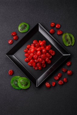 Kurumuş kırmızı kiraz veya koyu beton arka planda şekerli meyveler.