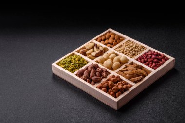 Ahşap bir kutunun içinde macadamia, çam, kaju, fındık, fıstık ve fıstık karışımı.