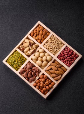 Ahşap bir kutunun içinde macadamia, çam, kaju, fındık, fıstık ve fıstık karışımı.