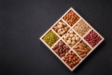 Ahşap bir kutunun içinde macadamia, çam, kaju, fındık, fıstık ve fıstık karışımı.