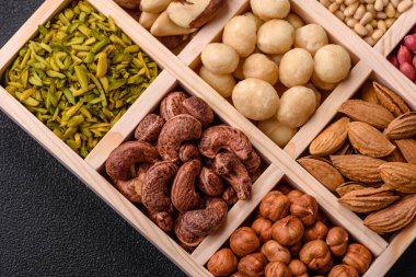 Ahşap bir kutunun içinde macadamia, çam, kaju, fındık, fıstık ve fıstık karışımı.