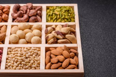 Ahşap bir kutunun içinde macadamia, çam, kaju, fındık, fıstık ve fıstık karışımı.