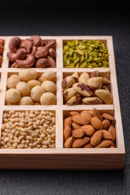 Ahşap bir kutunun içinde macadamia, çam, kaju, fındık, fıstık ve fıstık karışımı.