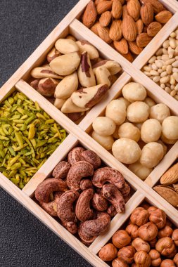 Ahşap bir kutunun içinde macadamia, çam, kaju, fındık, fıstık ve fıstık karışımı.