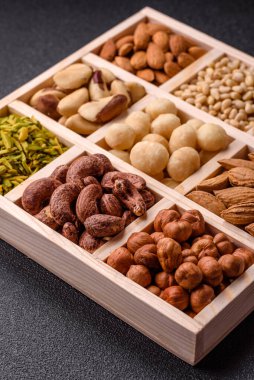 Ahşap bir kutunun içinde macadamia, çam, kaju, fındık, fıstık ve fıstık karışımı.