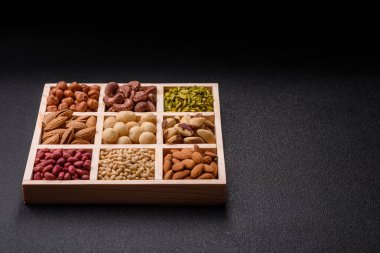 Ahşap bir kutunun içinde macadamia, çam, kaju, fındık, fıstık ve fıstık karışımı.