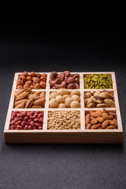 Ahşap bir kutunun içinde macadamia, çam, kaju, fındık, fıstık ve fıstık karışımı.