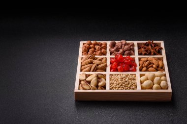 Ahşap bir kutunun içinde macadamia, çam, kaju, fındık, fıstık ve fıstık karışımı.